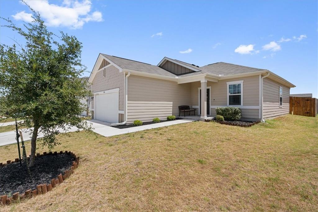 Single-story beige home with a two-car garage, covered entry, and front lawn.