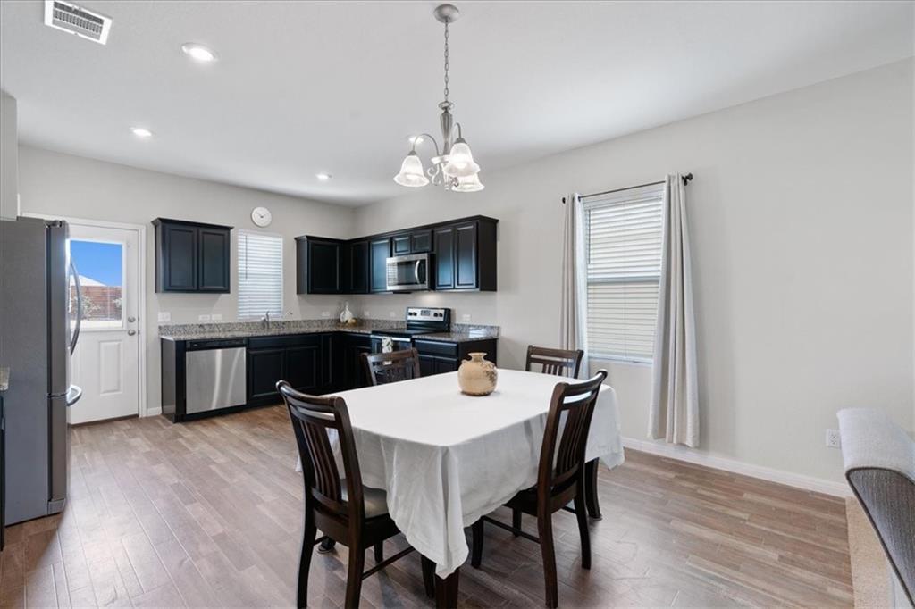 Kitchen and dining area with dark cabinets, stainless appliances, and a set dining table.