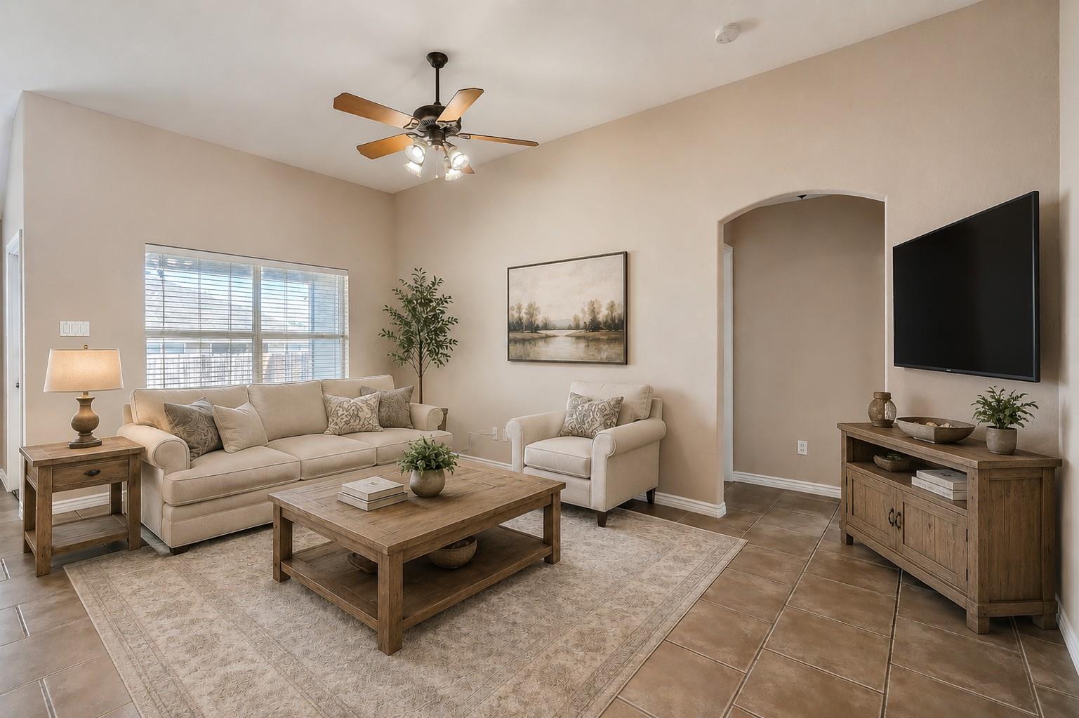 Living room with a beige sofa and armchair, wood coffee table, and ceiling fan.