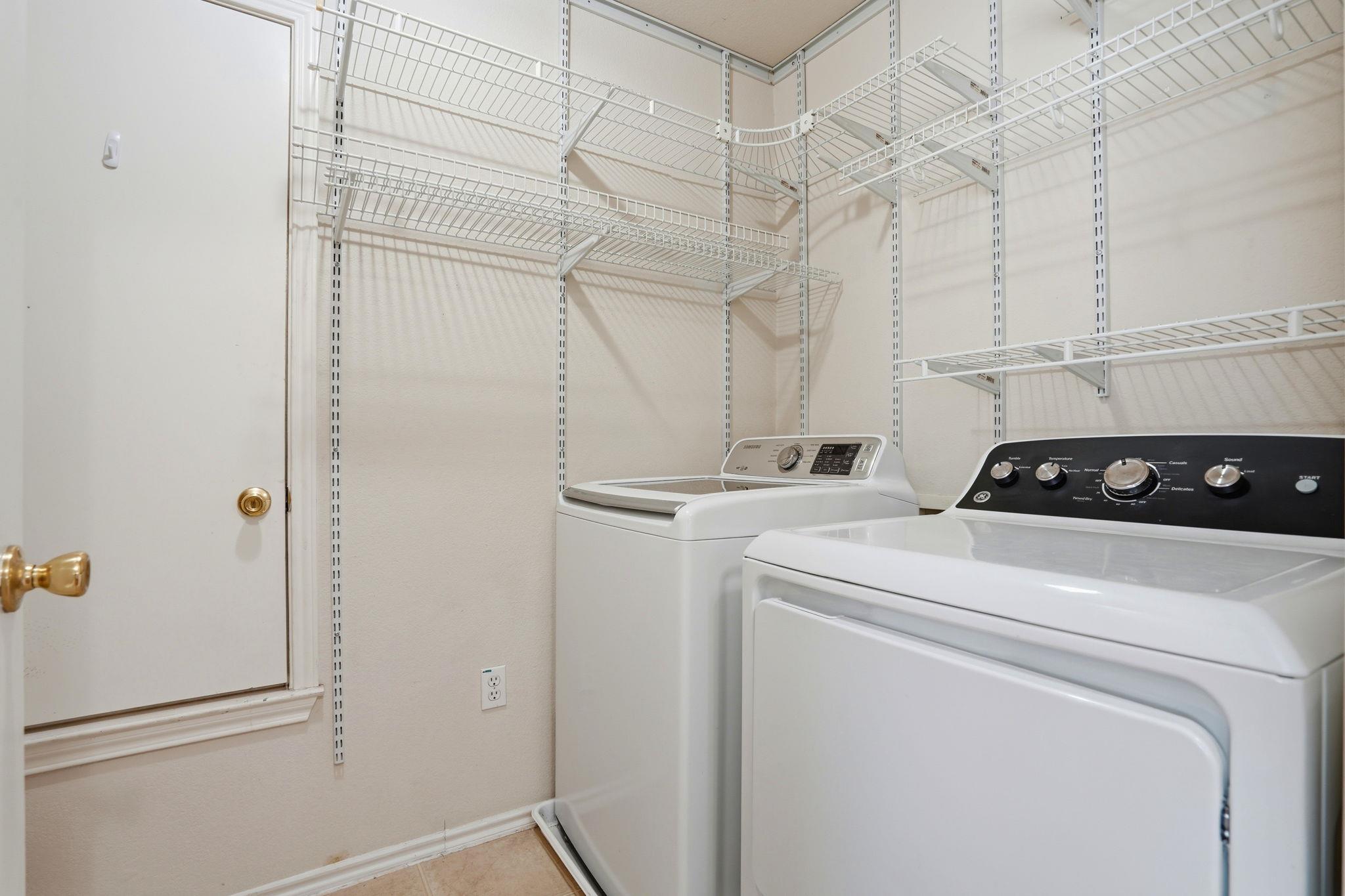 Laundry room with two top-loading machines and extensive wire shelving.