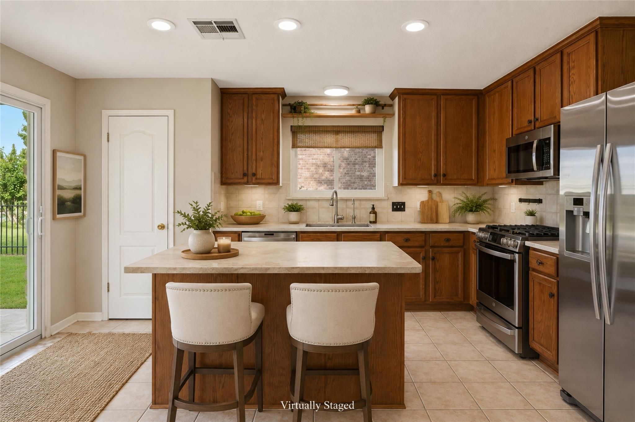 Kitchen with dark wood cabinets, stainless steel appliances, and a large island with two stools.