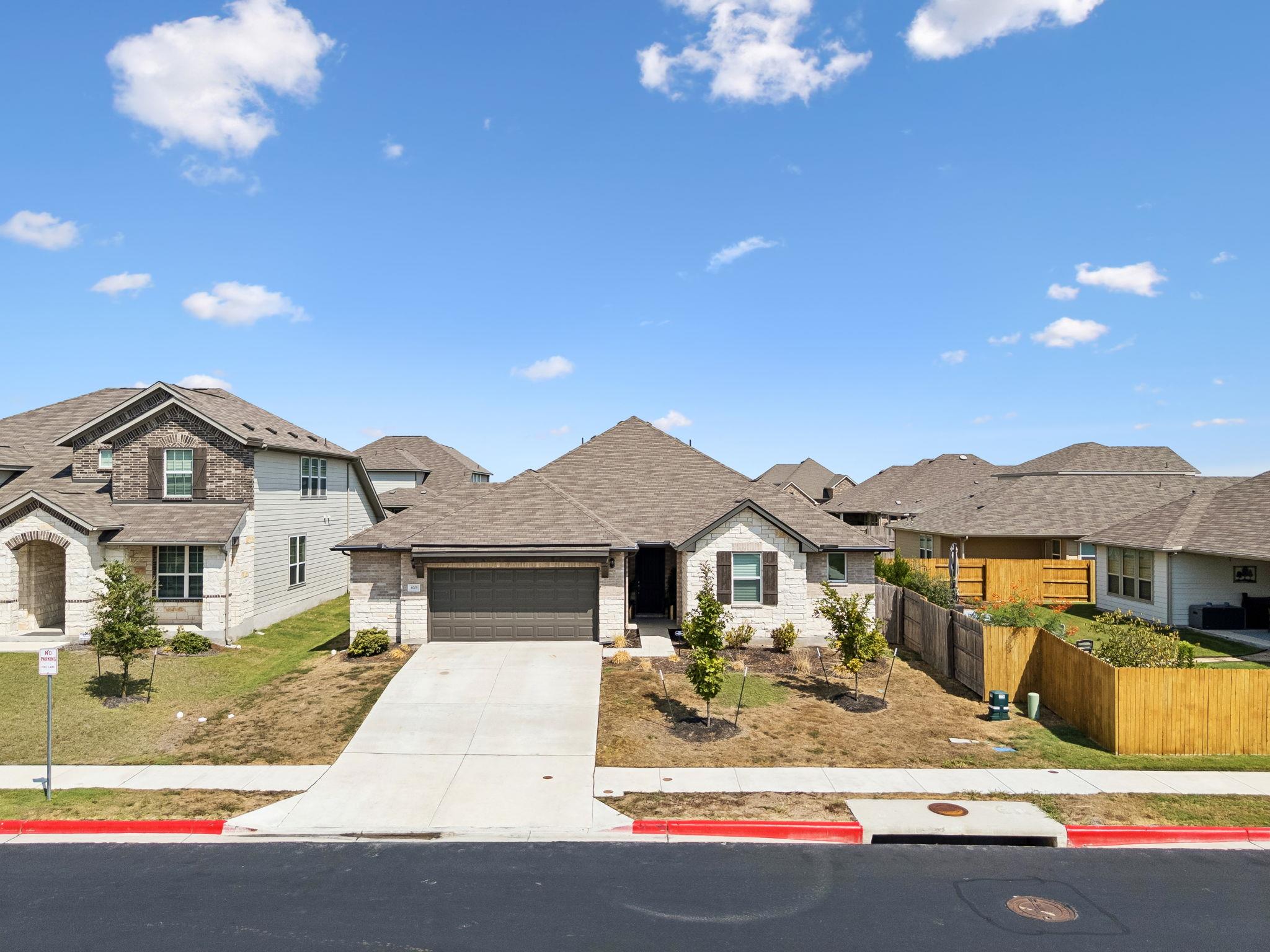 Single-story brick and stone house with a double garage, wide driveway, and fenced side yard.