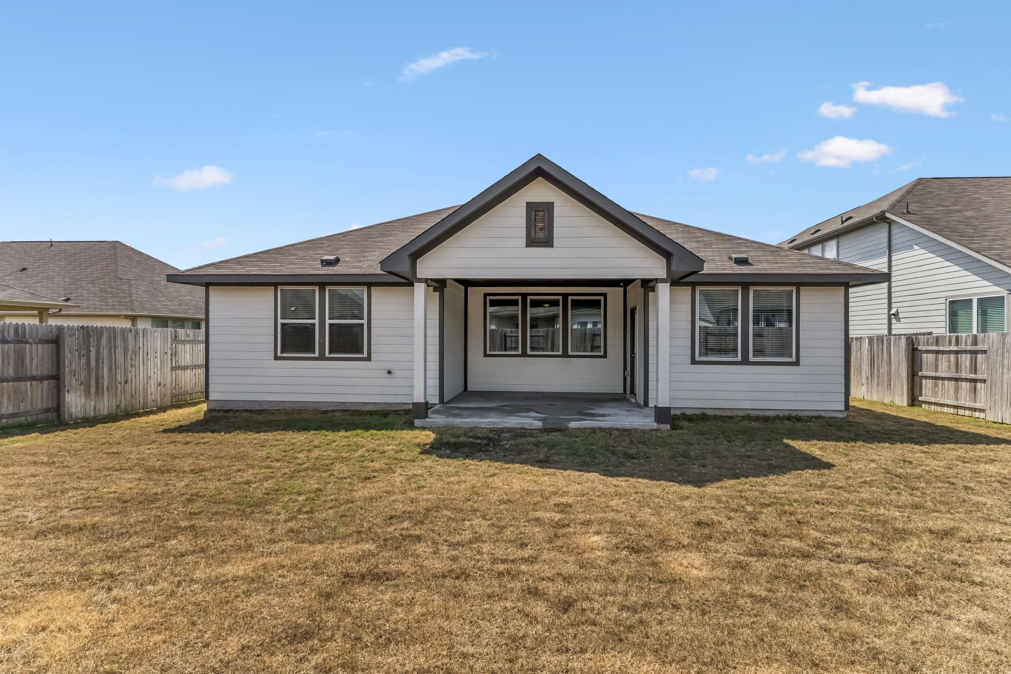 Gray single-story house with a covered rear patio and fenced yard.