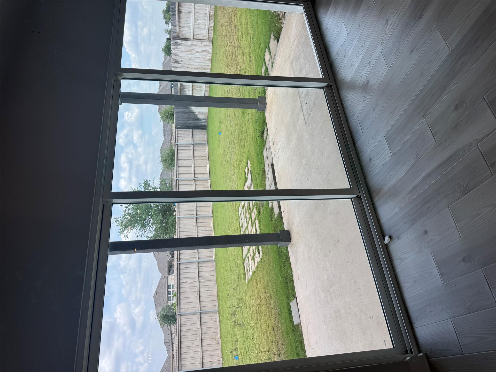 Sliding glass doors open onto a covered patio and fenced lawn with stepping stones.