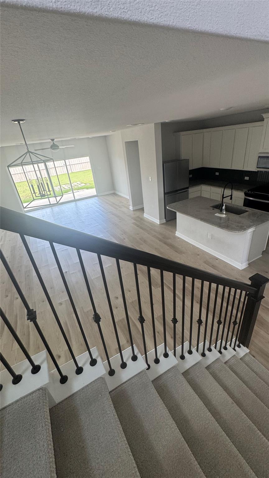 Open kitchen and dining area viewed from the stairs, with a gray island and sliding glass doors to the backyard.