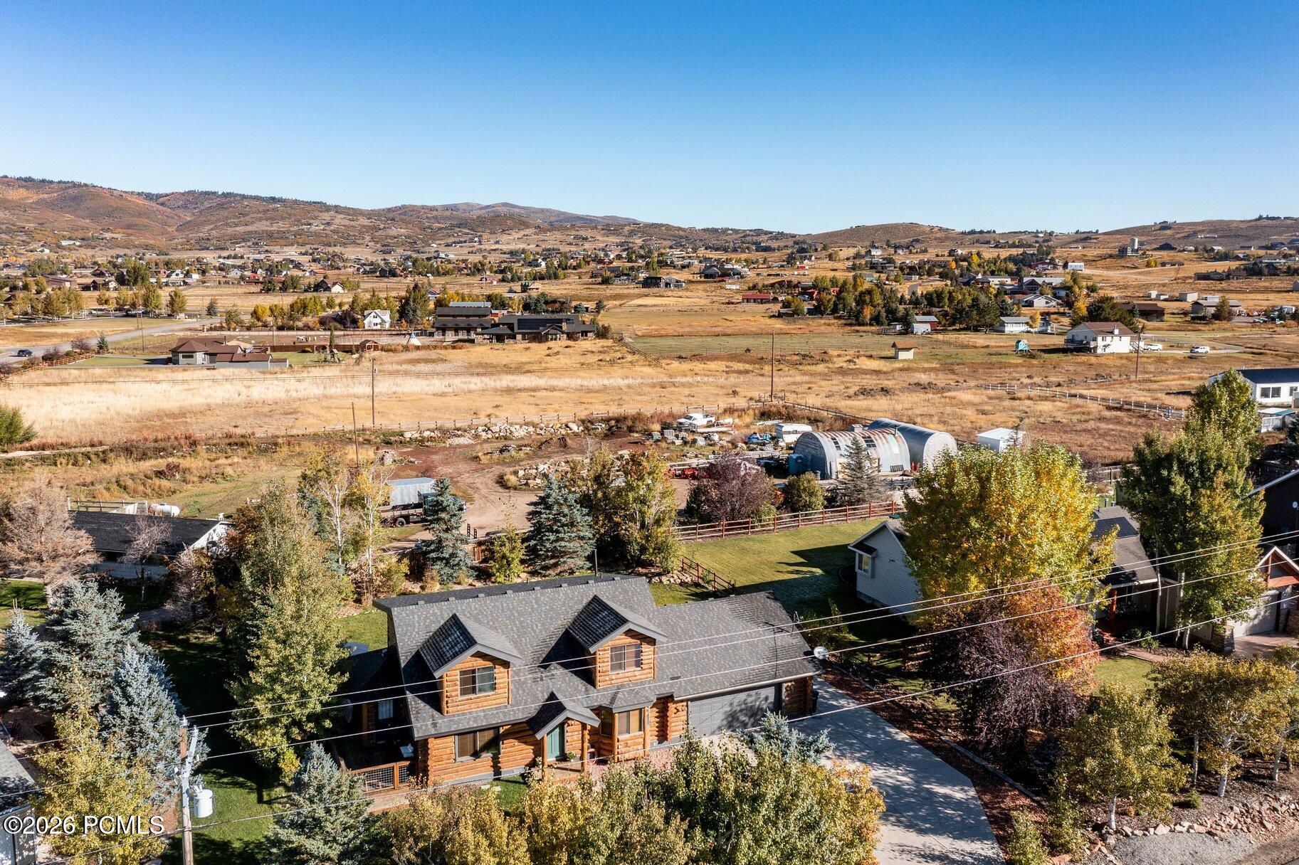 Log-style home overlooking open fields and rolling hills, framed by autumn trees.