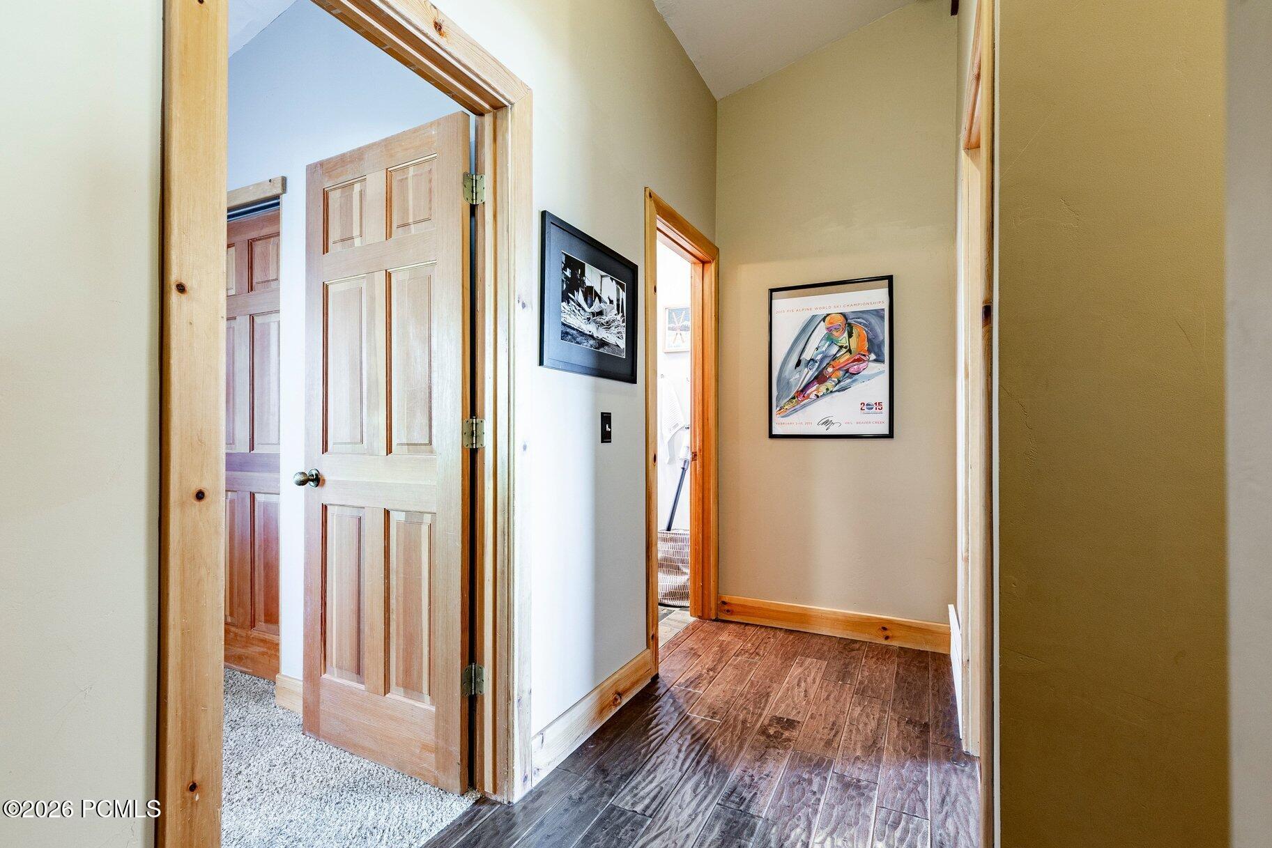 Hallway with wood-look flooring, natural wood trim, and framed ski artwork.