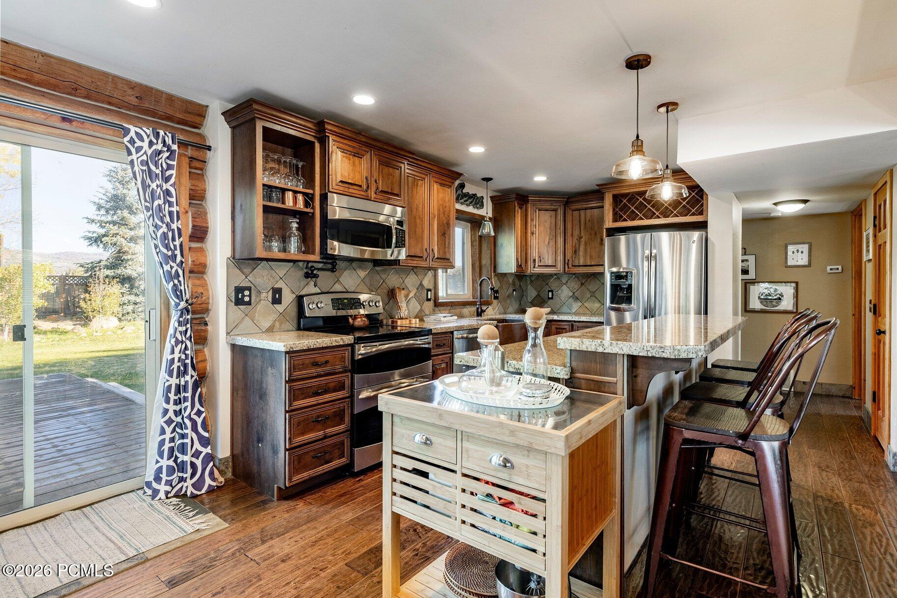 Kitchen with dark wood cabinets, stainless steel appliances, a central island, and a breakfast bar beside a deck door.