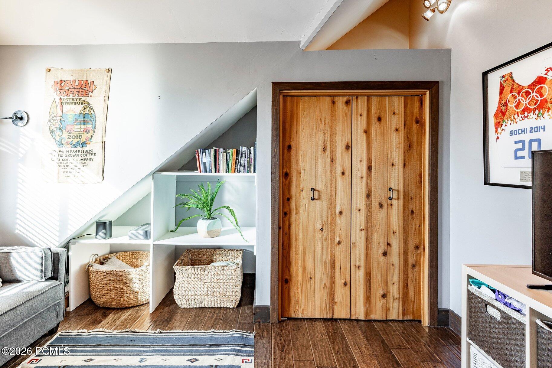 Furnished interior with rustic double doors, built-in shelving, a gray sofa, and woven baskets.