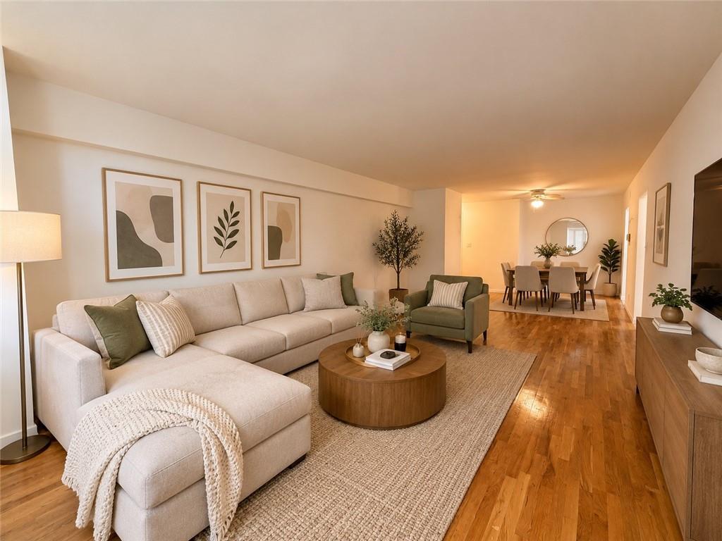 Living room with a cream sectional, green accent chair, and hardwood floors opening into a dining area.