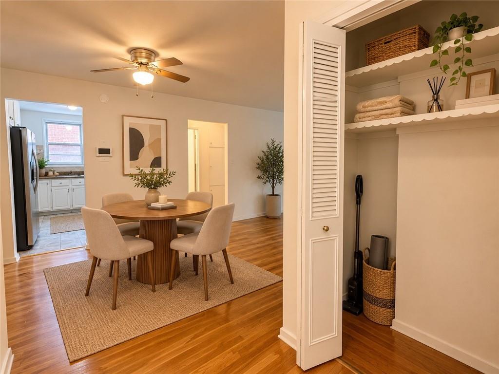 Dining area with a round wood table, woven rug, hardwood floors, and an open kitchen beyond.