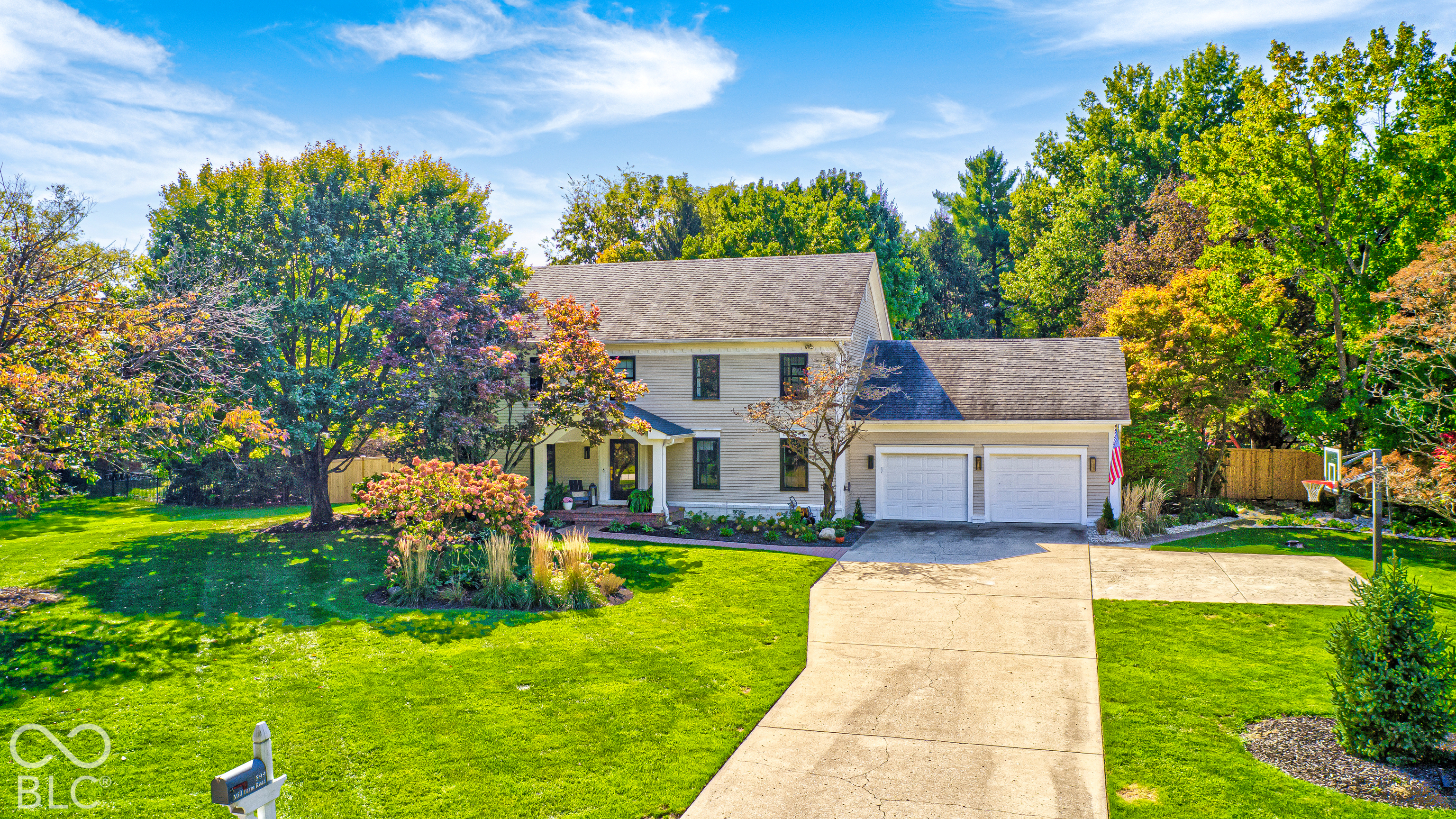 Two-story house with an attached two-car garage, landscaped yard, and basketball hoop beside the driveway.