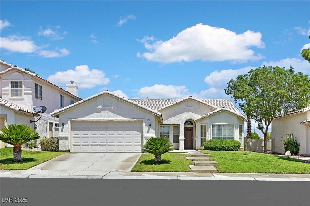 Single-story stucco home with a tiled roof, double garage, arched entry, and landscaped front lawn.
