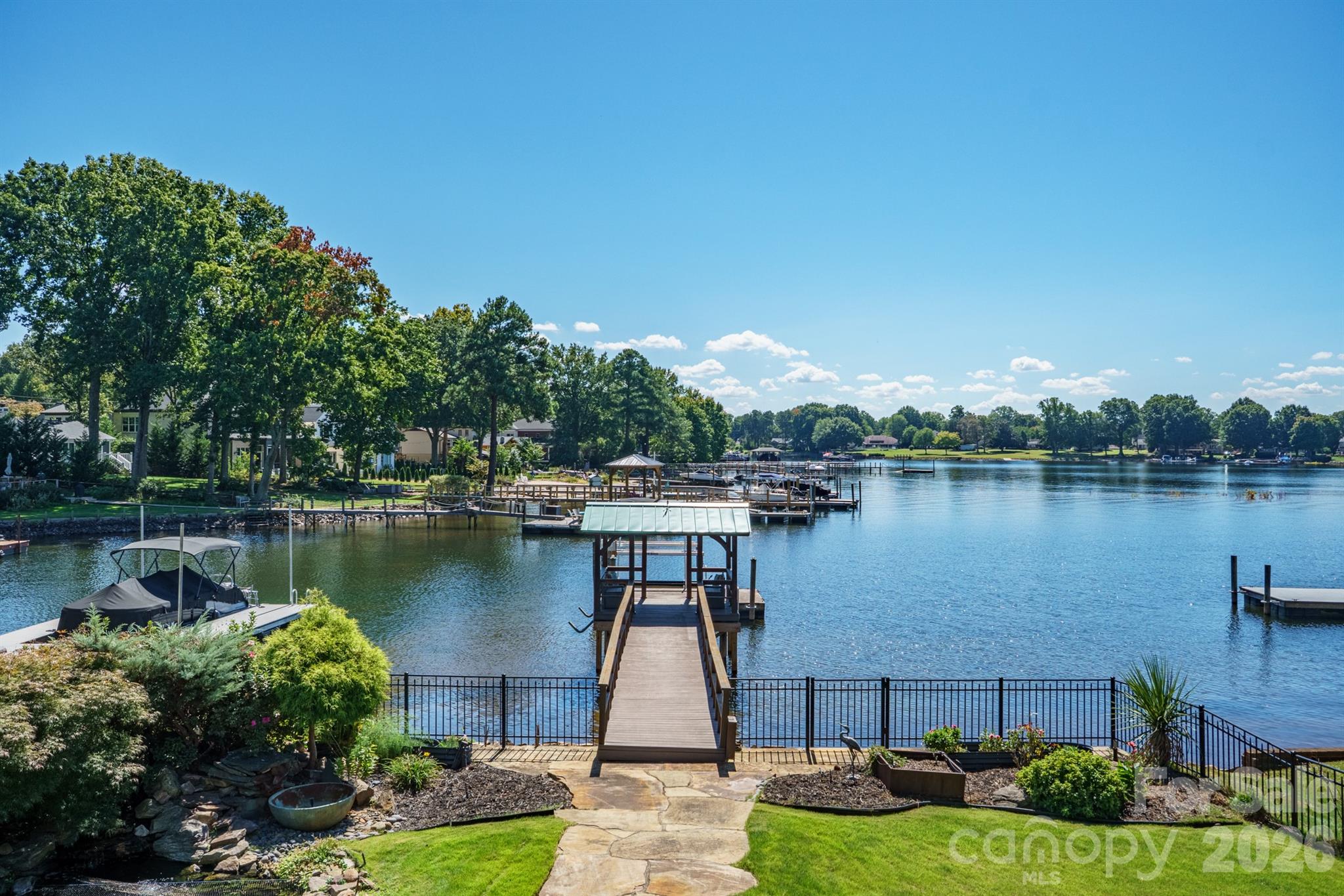 Lakefront backyard with a covered dock, stone walkway, and landscaped lawn.