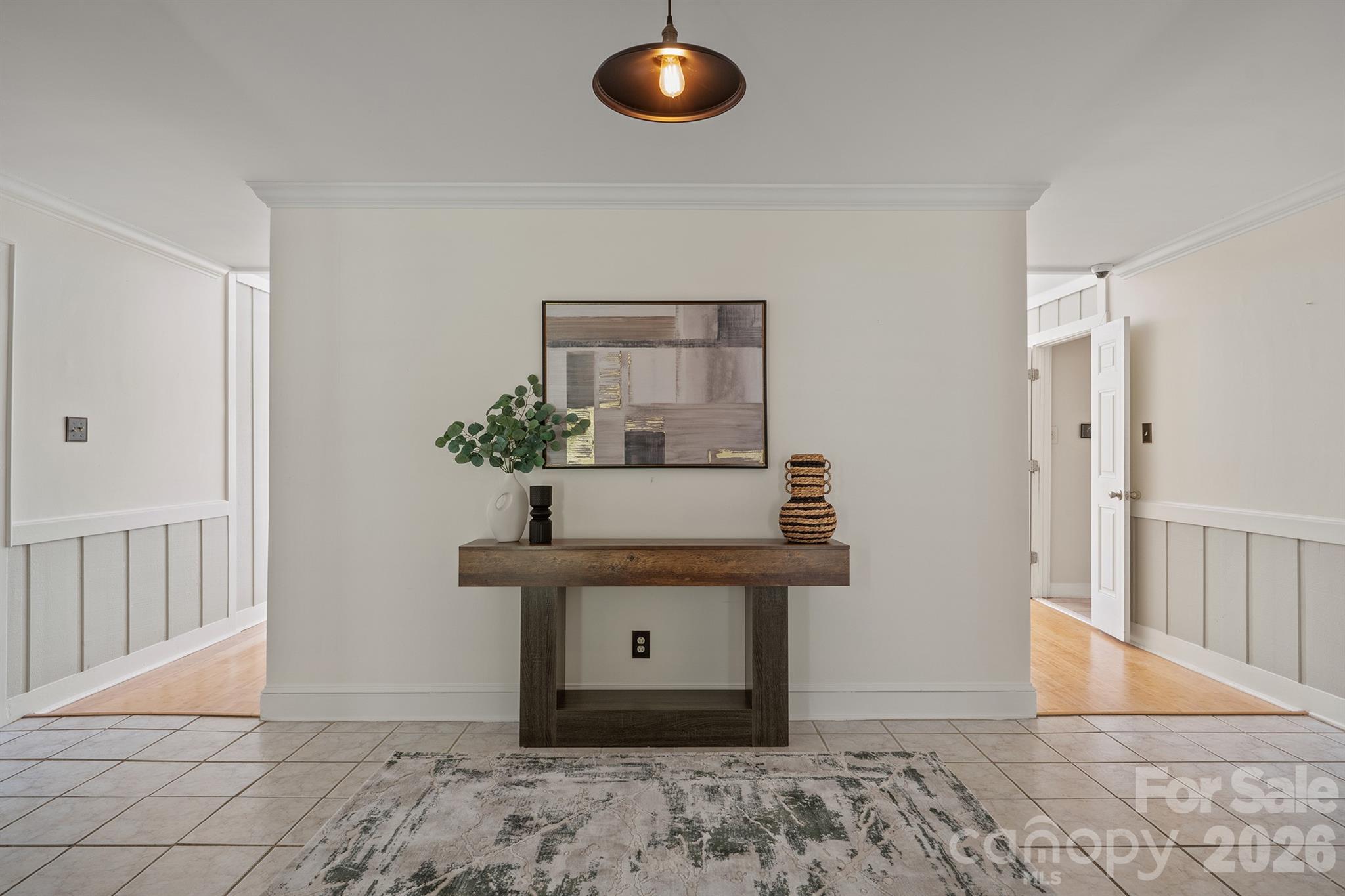 Entryway with a tiled floor, patterned rug, and console table beneath abstract art.