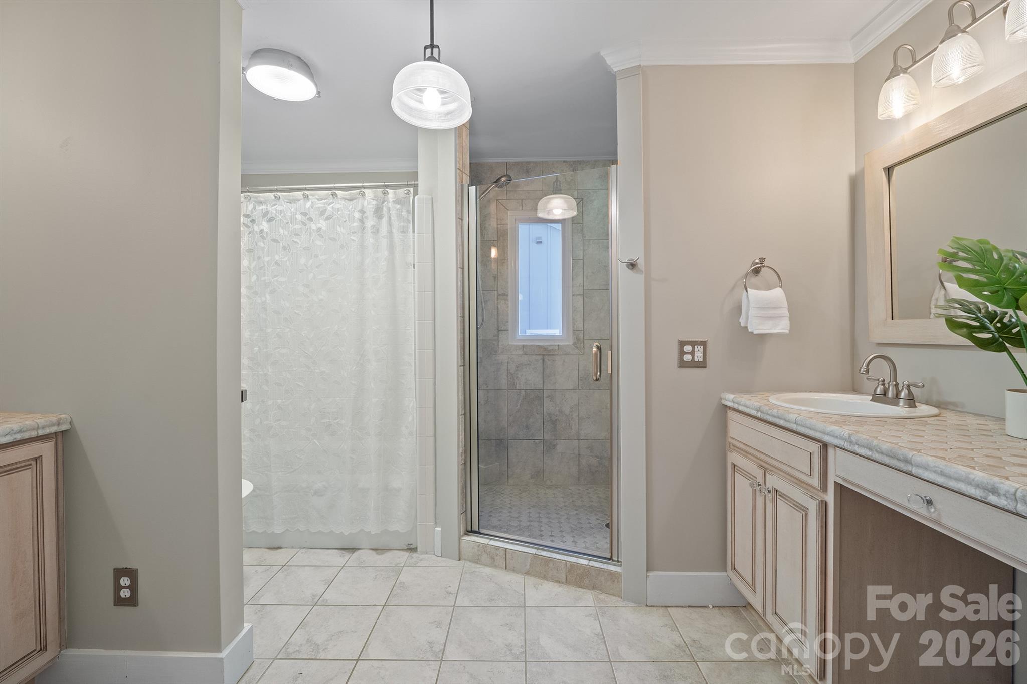 Bathroom with a glass-enclosed tiled shower, curtained tub, and light stone vanity.