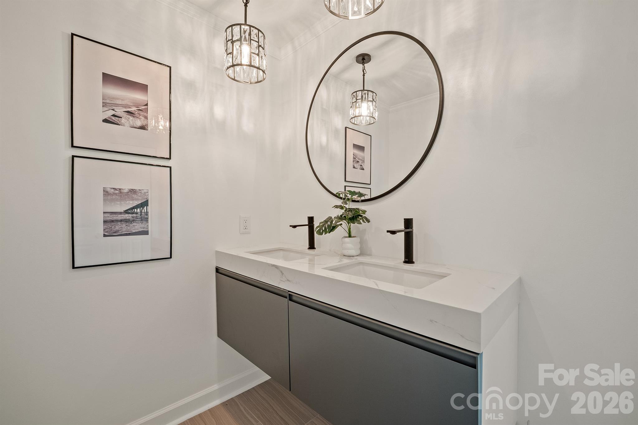 Modern double-sink bathroom vanity with a large round mirror and dark faucets.