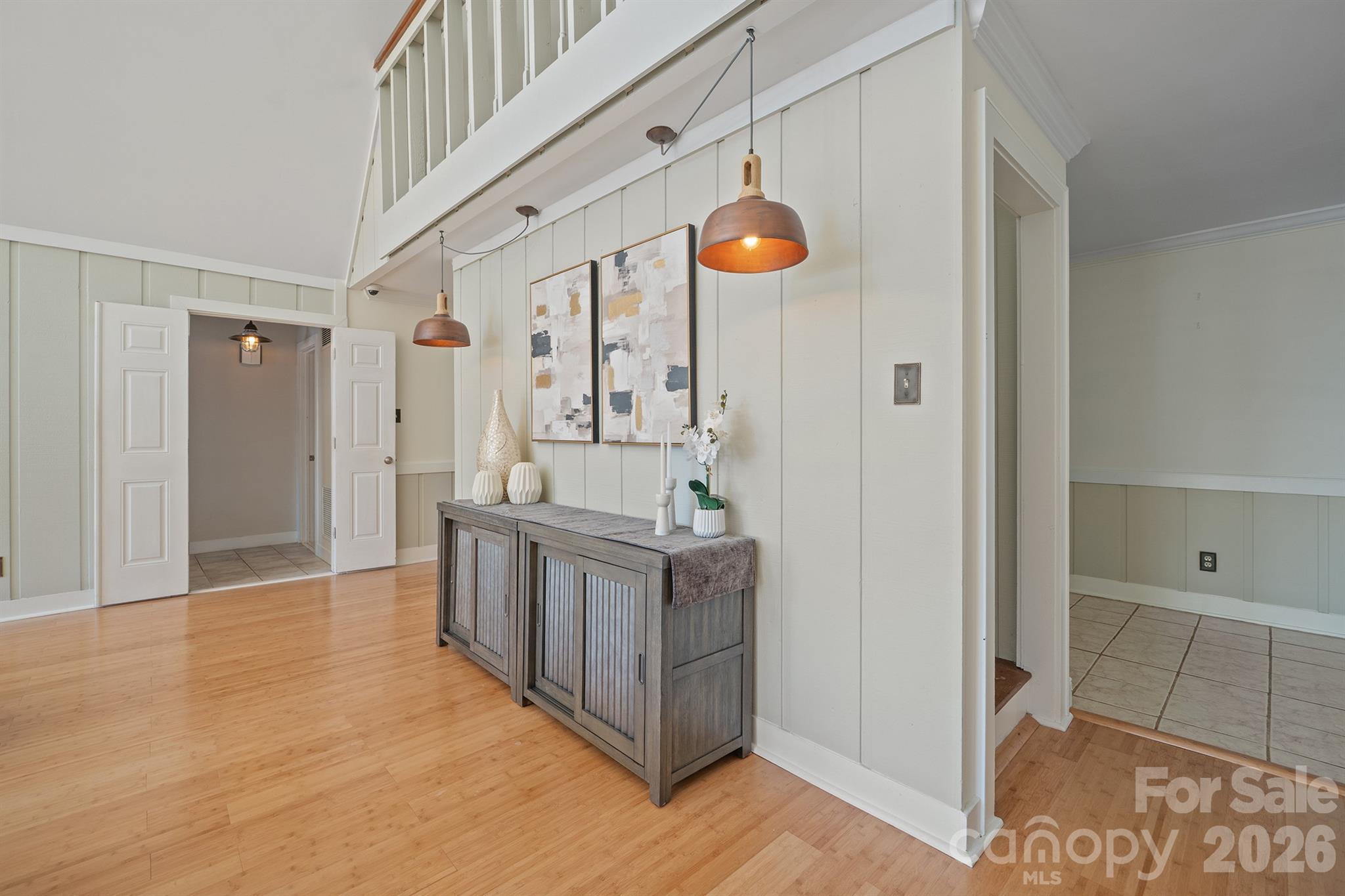 Entryway with a gray console cabinet, copper pendant lights, and an open upper-level railing.