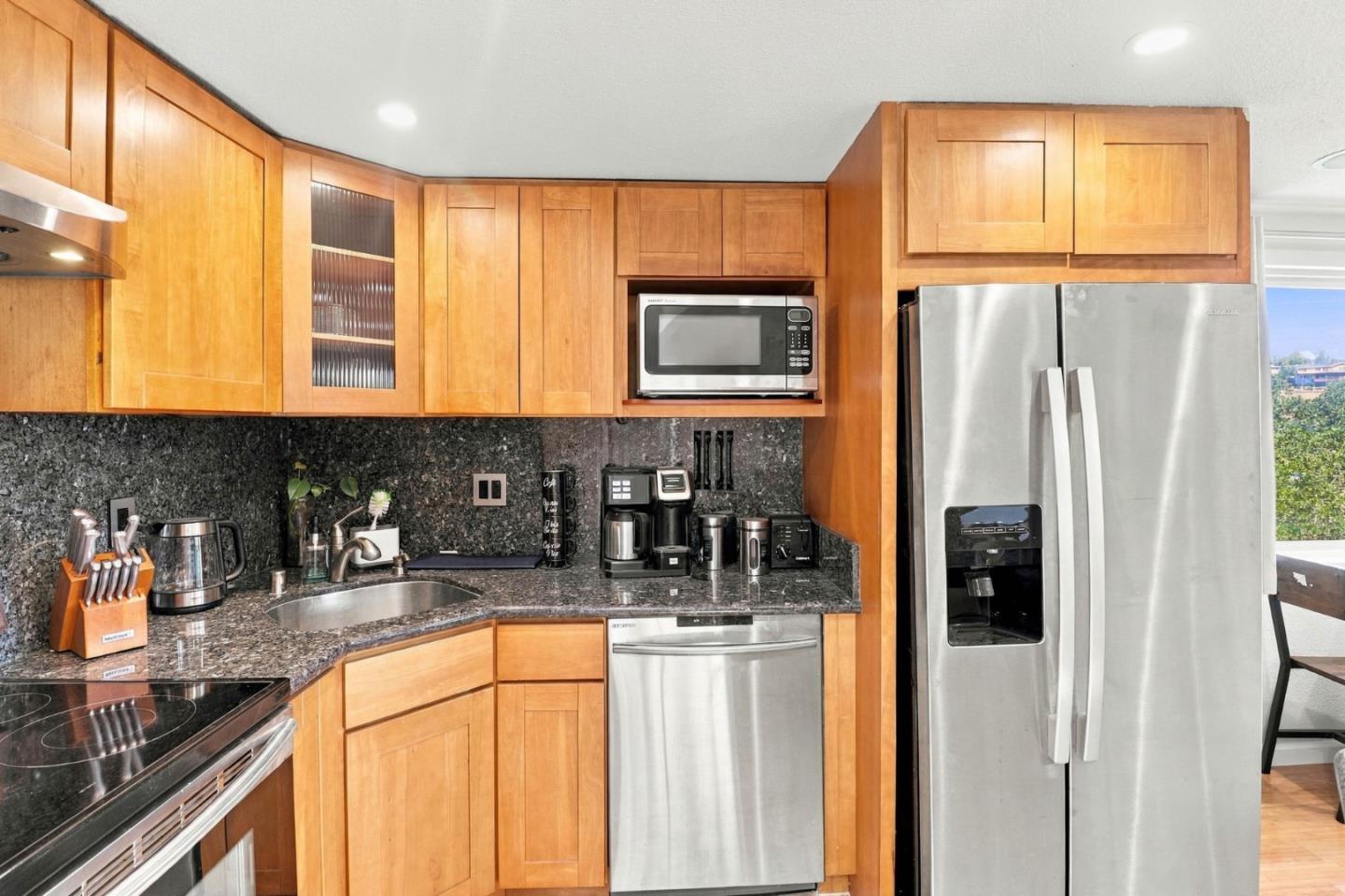 Kitchen with warm wood cabinets, dark granite counters, and stainless steel appliances.