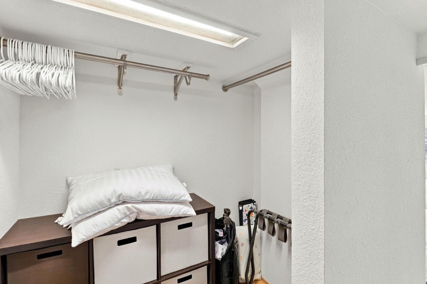 Walk-in closet with hanging rods, white hangers, and cube storage bins.