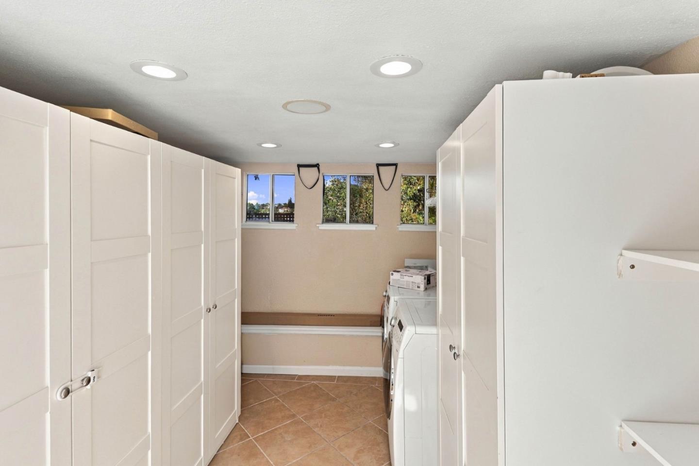 Laundry room with built-in white cabinets, washer and dryer, and windows at the far end.