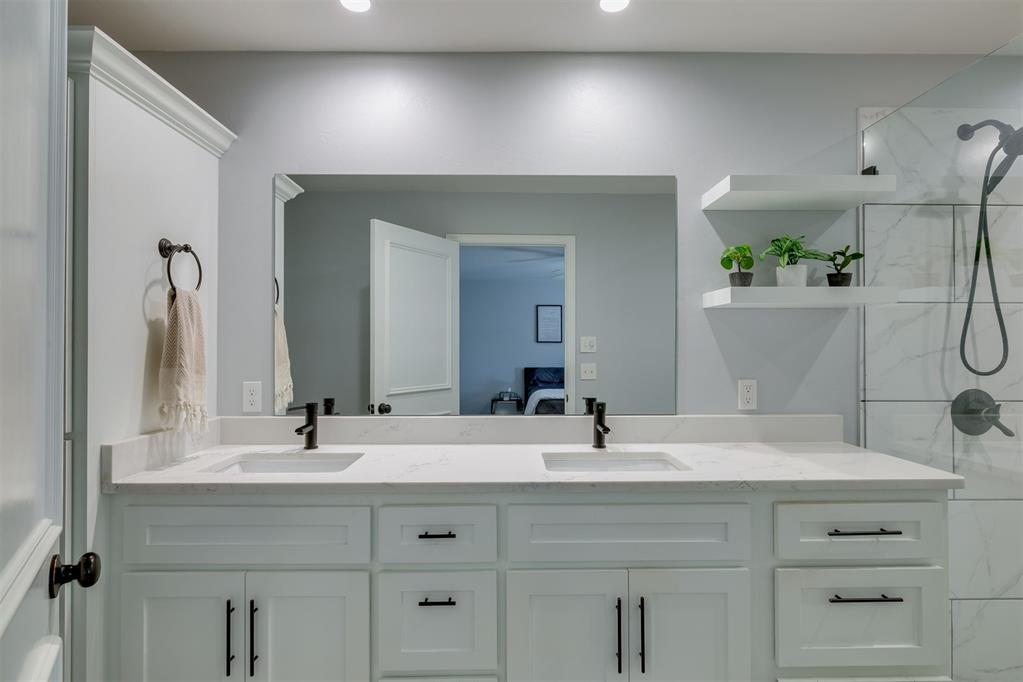 Bathroom with a white double-sink vanity, wide mirror, and glass-enclosed shower.
