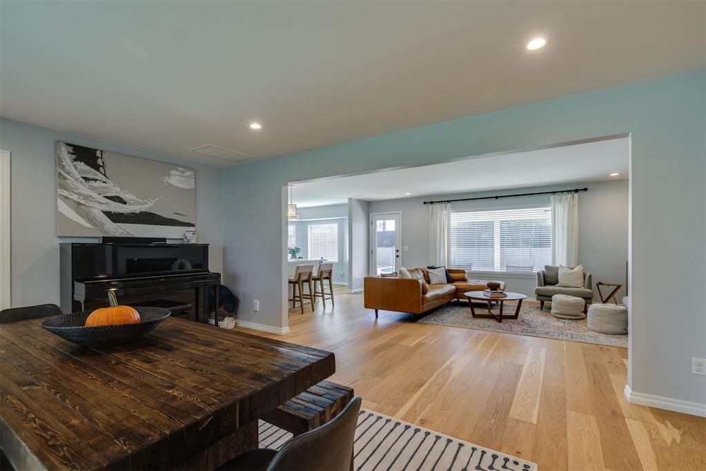 Open dining and living room with a dark wood table, piano, and tan sectional.