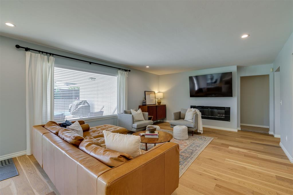 Living room with a caramel leather sofa, fireplace, and hardwood floors.