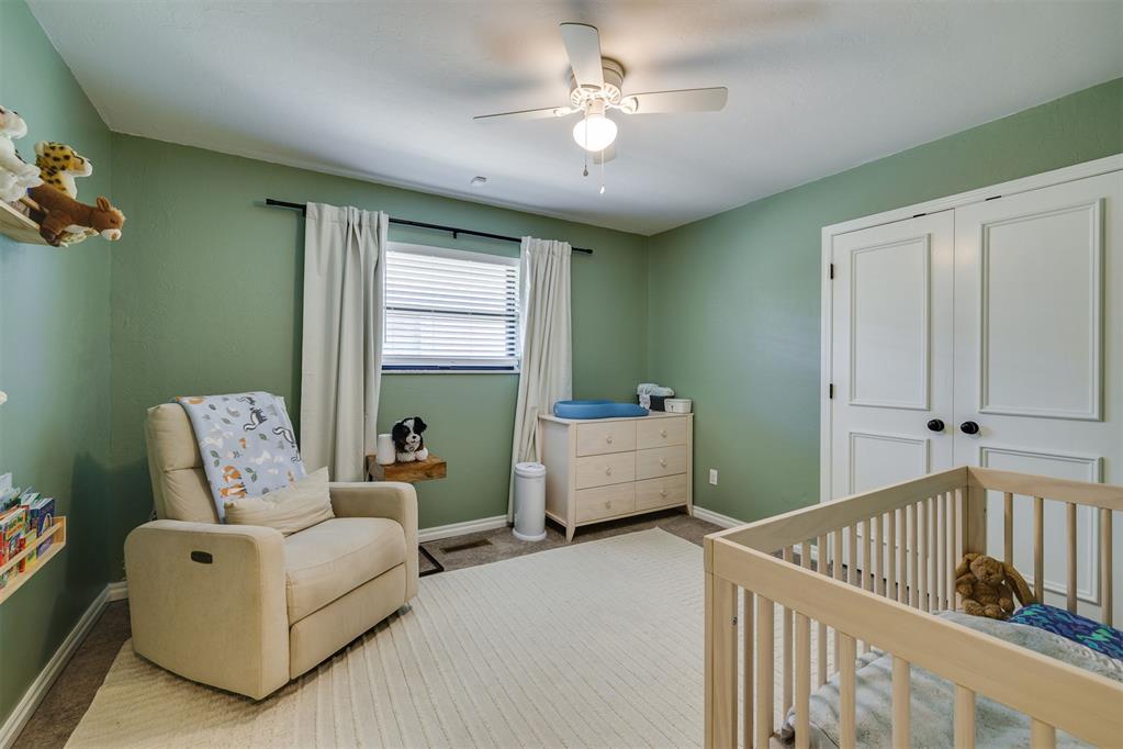 Nursery with a light wood crib, cream rocking chair, and sage green walls.