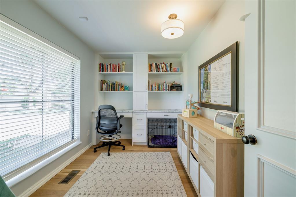 Home office with built-in bookshelves, a black desk chair, and a dog crate beneath the counter.