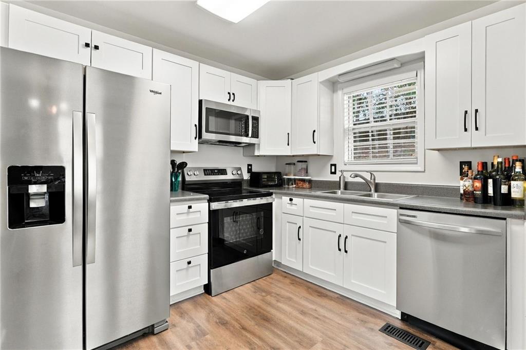 Kitchen with white shaker cabinets, stainless steel appliances, and a window above the sink.