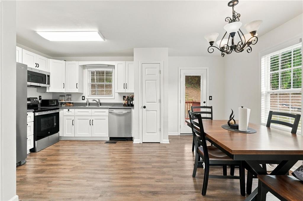 Kitchen and dining area with white cabinetry, stainless steel appliances, and a dark wood table.
