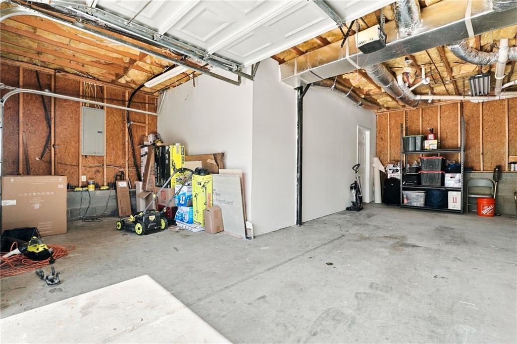 Garage with concrete floors, exposed framing, storage shelves, and a raised overhead door.