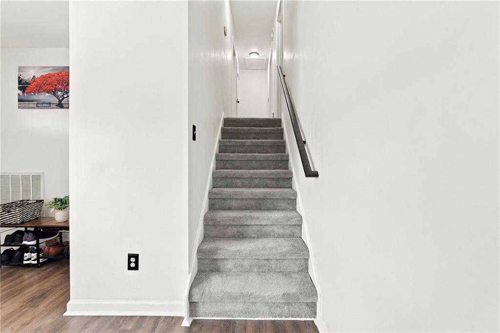 Carpeted staircase with a dark handrail leading to an upper hallway.