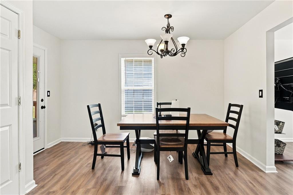 Dining room with a wood-top table, four dark chairs, and a decorative chandelier.