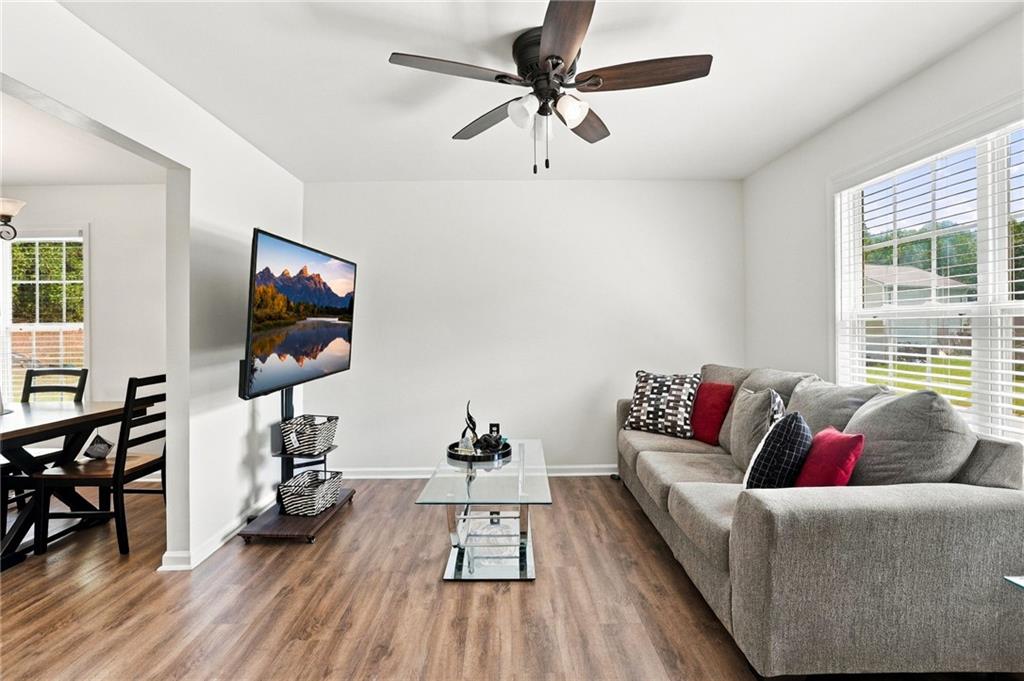 Living room with gray sectional, glass coffee table, ceiling fan, and adjoining dining area.