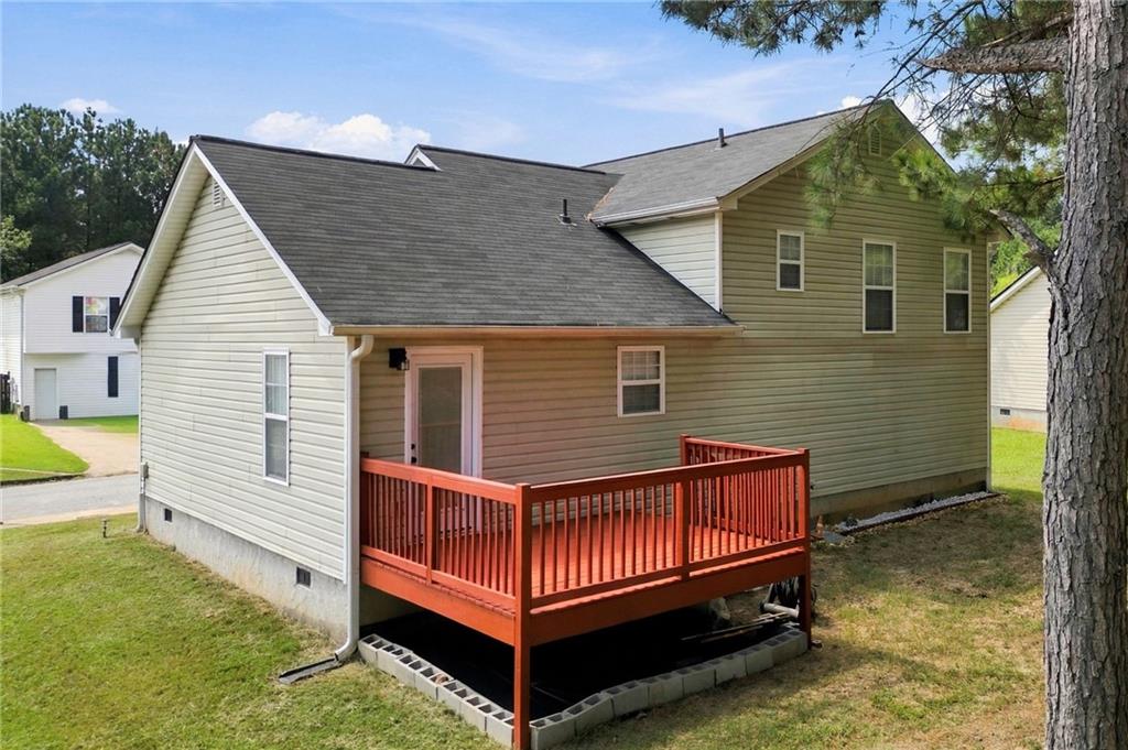 Rear exterior of a two-story house with a raised red-railed deck and gray shingle roof.