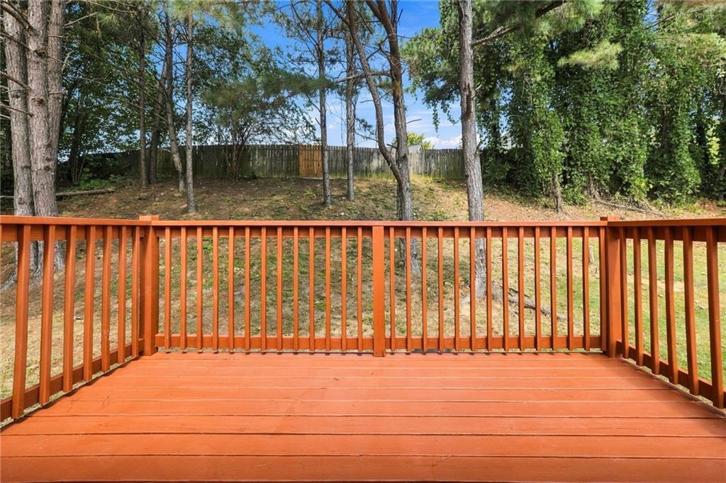 Orange wooden deck overlooking a tree-lined backyard enclosed by a wooden fence.
