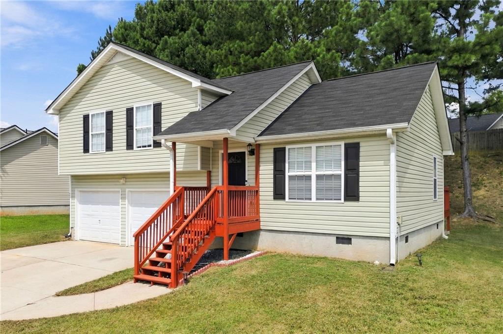 Beige split-level house with a red-orange front porch and stairs, attached two-car garage, and concrete driveway.