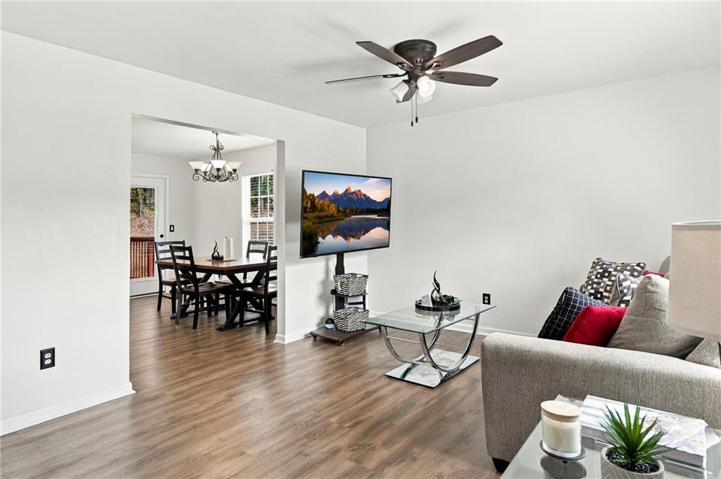 Living room with a ceiling fan and glass coffee table, opening into the dining area.