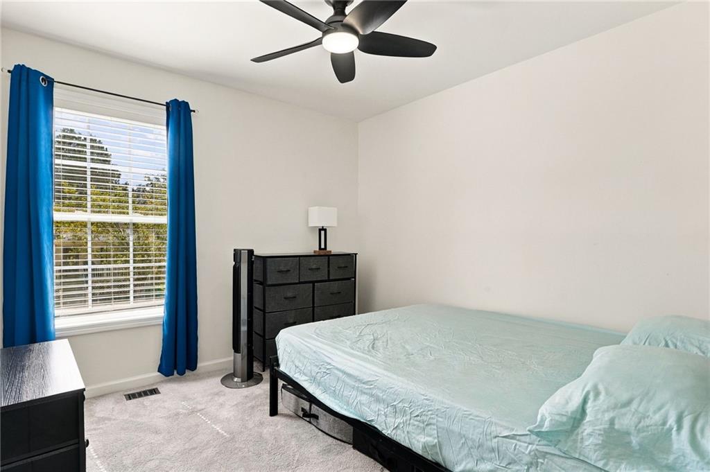 Bedroom with pale aqua bedding, bright blue curtains, and a dark ceiling fan.
