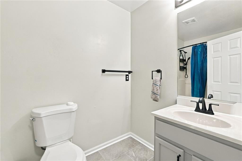 Bathroom with a gray vanity, white toilet, large mirror, and blue shower curtain.