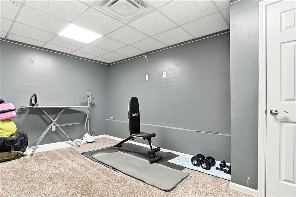 Home exercise room with a weight bench, dumbbells, exercise mat, and ironing board.
