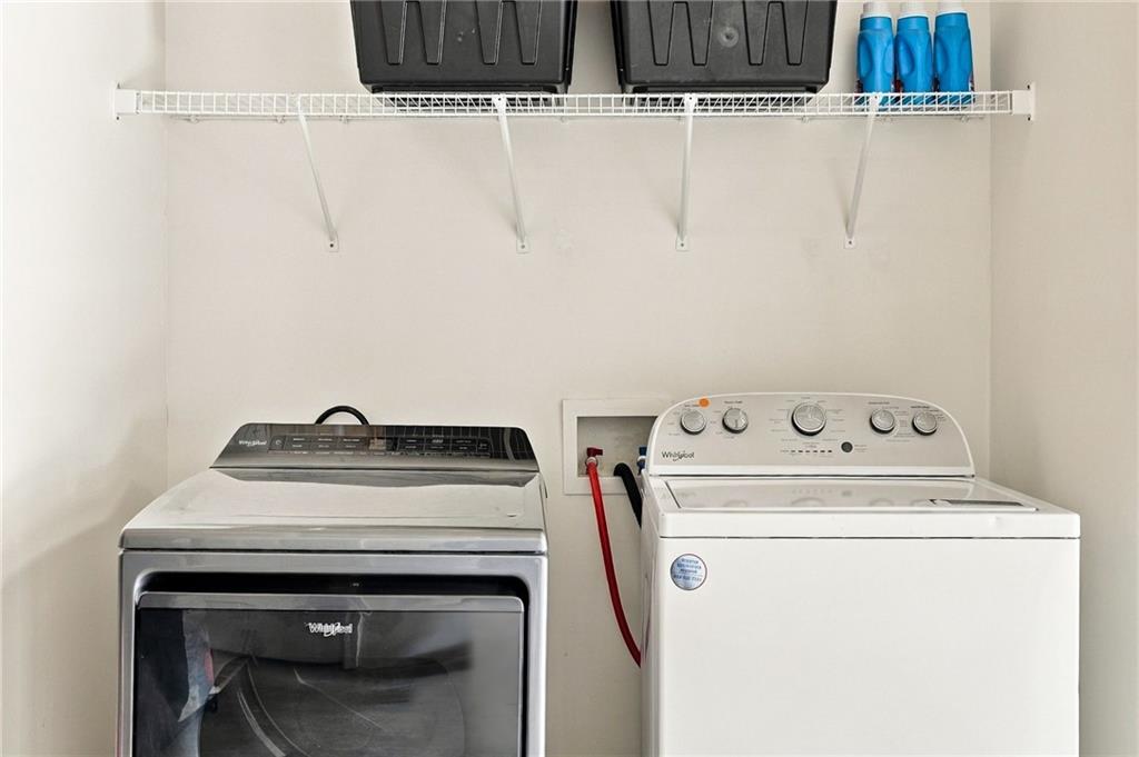 Laundry room with a front-loading dryer, top-loading washer, and storage shelf above.