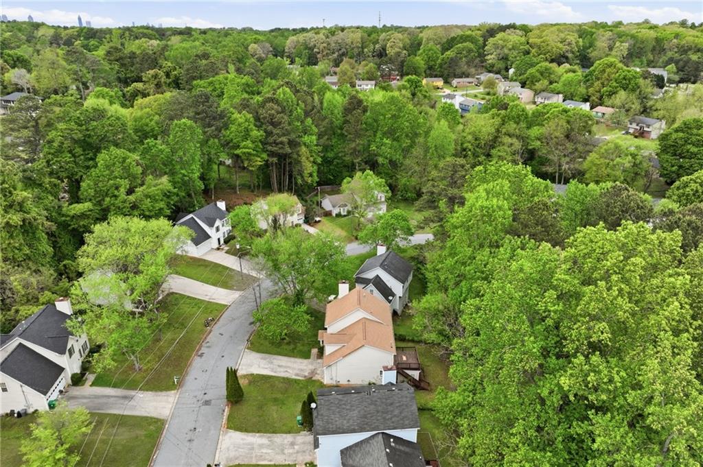 Aerial view of homes along a curving street amid dense green woodland.