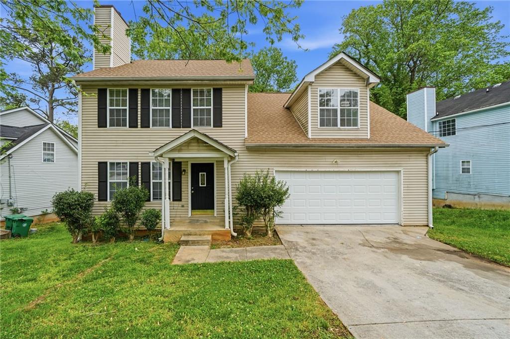 Two-story beige house with black shutters, a white garage, and a covered front entry.