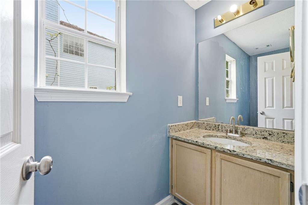 Bathroom with a granite-topped vanity, large mirror, blue walls and a window.