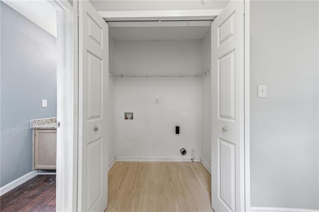 Empty laundry closet with washer and dryer hookups, a wire shelf, and open double doors.