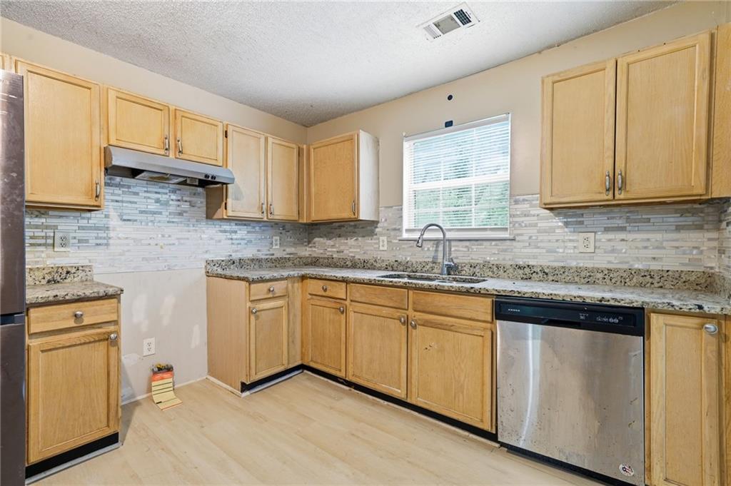 Kitchen with light wood cabinets, granite countertops, and a window above the sink.