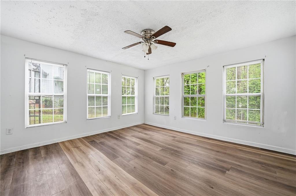 Empty room with six windows, a ceiling fan, and wood-look plank flooring.